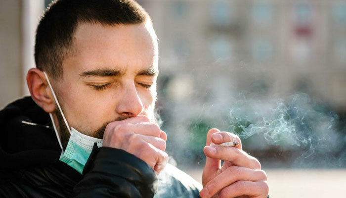 man coughing while smoking cannabis